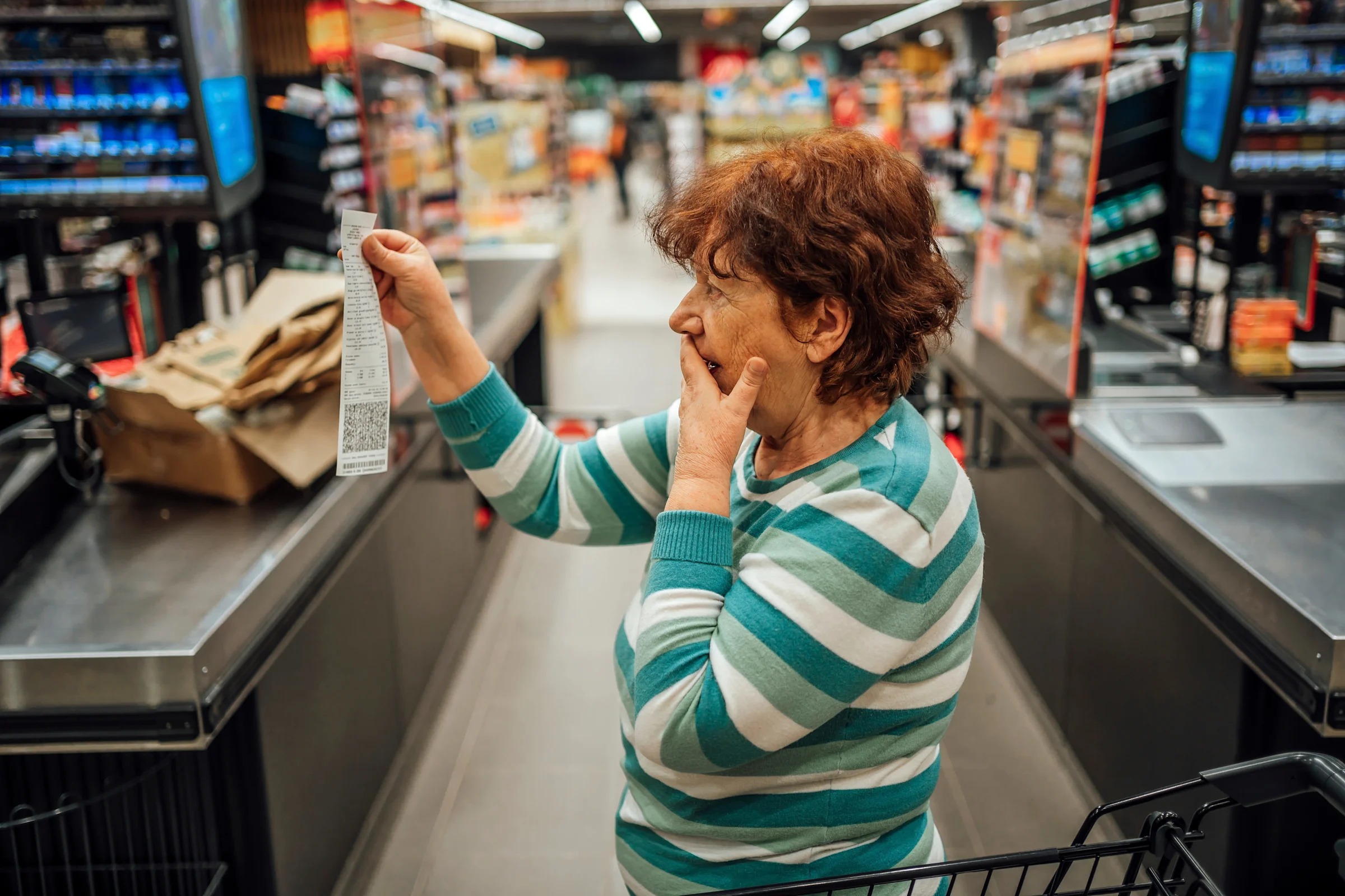 Person looking at a long paper receipt in a grocery store